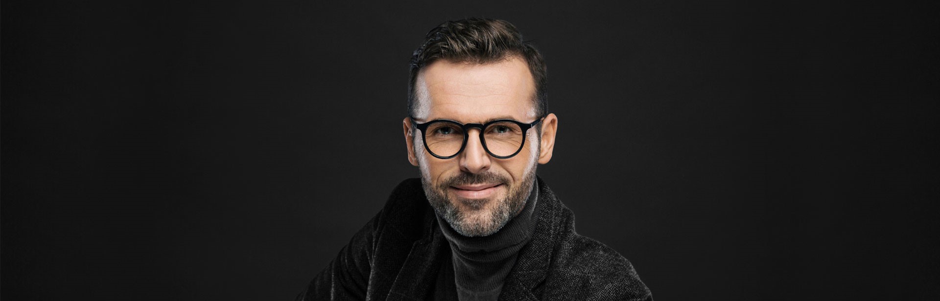 Man with glasses on bold dark background